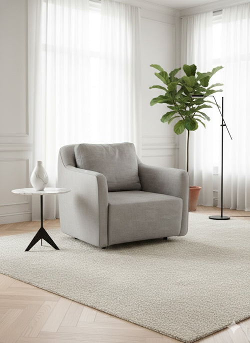Side profile of the Antibes armchair in light grey fabric with clean lines