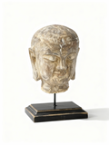 Asian statue head on a pedestal with soft lines and meditative expression