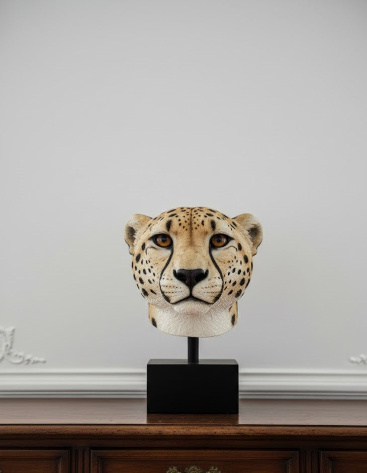 Hyper-realistic cheetah head sculpture with detailed coat and black tear marks, elegantly mounted on a matte black pedestal