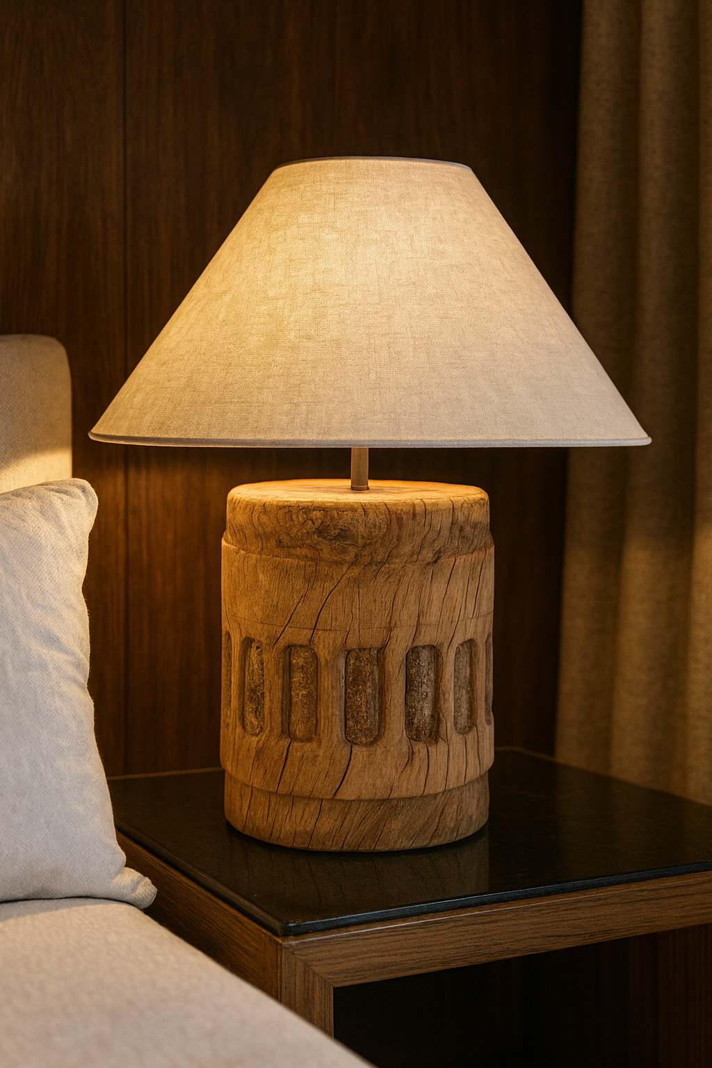Table lamp with a raw, cylindrical solid wood base featuring carved patterns, natural cracks, and topped with an ecru conical fabric lampshade