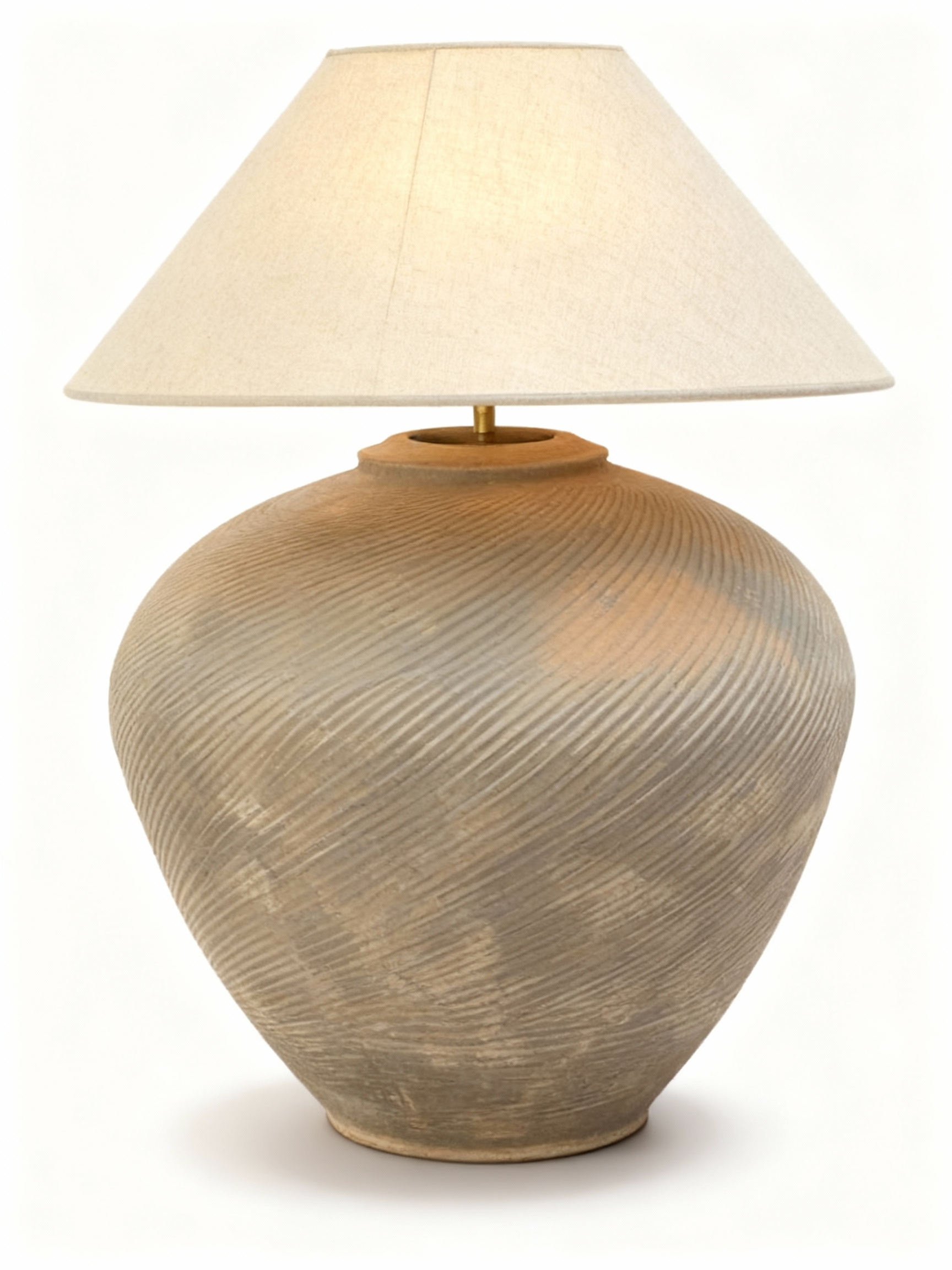 Artisan table lamp with a tall, textured, rustic pot base featuring relief striations and an aged patina. Topped with a large, light-toned conical lampshade.